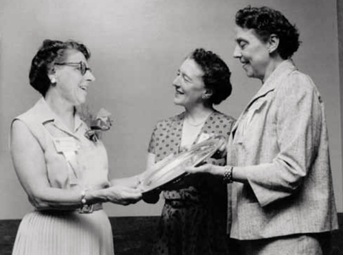 President Mildred Elson is presented with a salver by two women standing next to her.