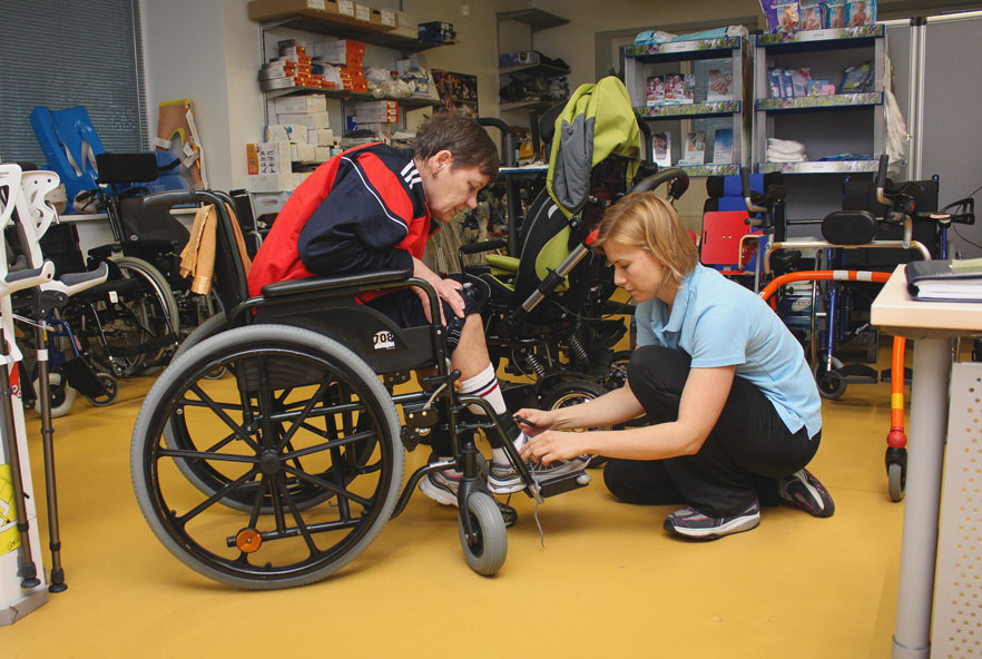 A physiotherapist attends to a person in a wheelchair