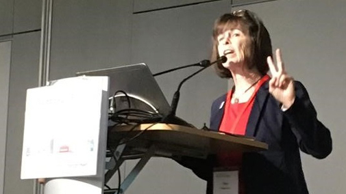 Ann Newstead stands on stage presenting her research