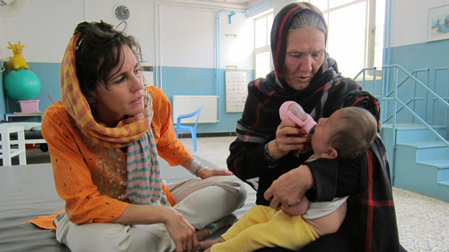 Lorena Enebral with an older woman bottle feeding a baby