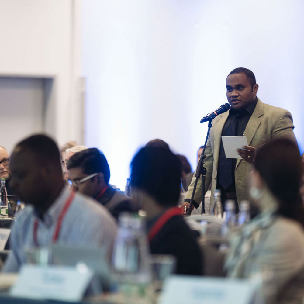 A man stands to speak during the General Meeting