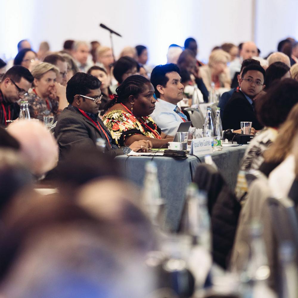 General Meeting attendees sitting at rows of tables