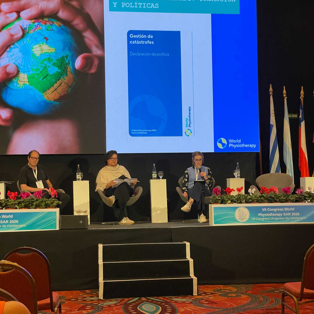a panel discussion on stage with a screen showing hands on a globe