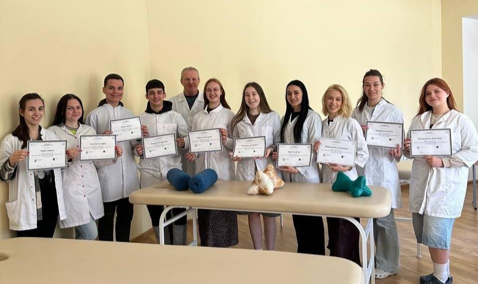 A group of physiotherapists standing in a classroom holding certificates