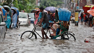 Man cycles through water in city street